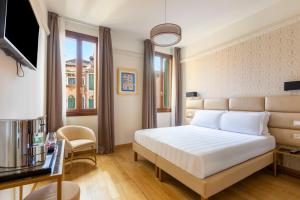 a hotel room with a bed and a television at Numa Venice Palazzo Orseolo in Venice