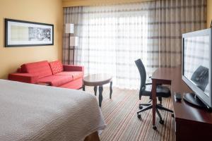 um quarto de hotel com uma cama, uma secretária e uma televisão em Courtyard by Marriott Indianapolis Airport em Indianápolis