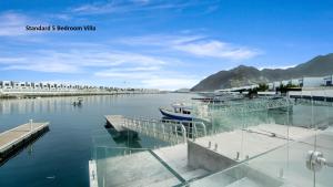 a boat is docked at a dock in the water at Al Dana Paradise Luxury Villas Palm Fujairah Sea View in Fujairah