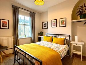 een slaapkamer met een bed met gele lakens en een raam bij Comfy Home within City Wall, 10 mins Walk to Centre, Attractions & Railway Station in York