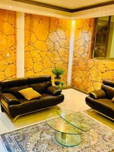 a living room with a leather couch and a stone wall at GoldenWays Motel 2 in Mbabane