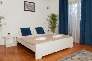 uma cama branca num quarto com cortinas azuis em Red Clay Spa Apartments em Belgrado