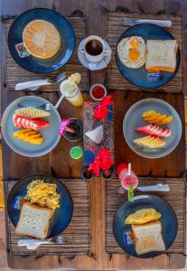 una mesa de madera cubierta con platos de desayuno en Blue Lagoon Secret Villas, en Nusa Lembongan