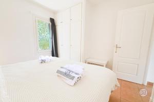 a white bedroom with two towels on a bed at The Desmais in Cala Galdana