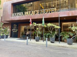 un edificio con banderas y plantas delante de él en Marwa Palace Hotel Cairo en El Cairo