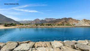 a body of water with mountains in the background at Al Dana Paradise Luxury Villas Palm Fujairah Sea View in Fujairah