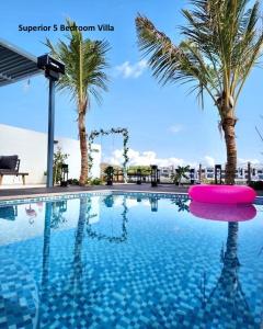 a swimming pool with palm trees in the background at Al Dana Paradise Luxury Villas Palm Fujairah Sea View in Fujairah