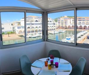 un tavolo con sedie e vista su un porto turistico di La Perle Marine, Cosy et rénové, 200 m de la plage, 1 chambre, parking et Wifi a Sète