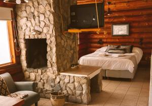 a bedroom with a bed and a stone fireplace at Ruma Andina by DOT Cabana in Villa La Angostura