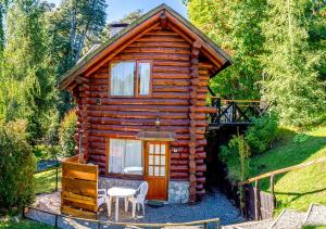 a log cabin with a table and chairs in front of it at Ruma Andina by DOT Cabana in Villa La Angostura