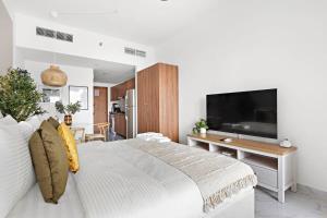 1 dormitorio con 1 cama blanca grande y TV en Silkhaus Chic Studio Near Masdar City Park, en Yas Island