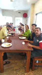 un groupe de personnes assises autour d'une grande table en bois dans l'établissement Ramraj Resort, à Kânyâkumârî