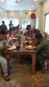 Un groupe de personnes assises à une table et mangeant de la nourriture dans l'établissement Ramraj Resort, à Kânyâkumârî