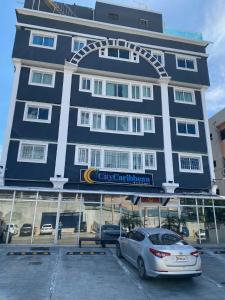 un edificio azul con un coche aparcado en un estacionamiento en City Caribbean Hotel Boutique, en Santo Domingo