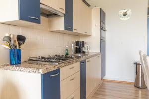 La cuisine est équipée de placards bleus et d'un four avec plaques de cuisson. dans l'établissement Duinerei appartement C102, à Callantsoog