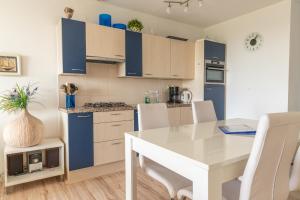 une cuisine avec une table blanche et des armoires bleues dans l'établissement Duinerei appartement C102, à Callantsoog