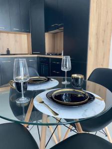 - une table en verre avec 2 assiettes et des verres à vin dans l'établissement Gold Star Black Cosmopolis, à Creţuleasca