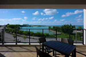 einen Balkon mit einem Tisch und Stühlen sowie Blick auf das Wasser in der Unterkunft Hotel & Villa Seahorse MIYAKOJIMA in Miyako-jima