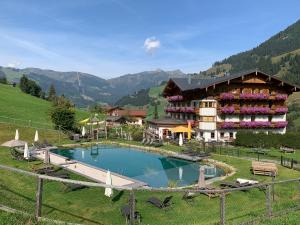 un complexe avec une grande piscine dans un champ dans l'établissement Hotel Lammwirt, à Grossarl