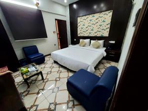 a bedroom with a bed and two blue chairs at Diplomat Inn Hotel in Karachi