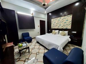 a bedroom with a bed and two blue chairs at Diplomat Inn Hotel in Karachi