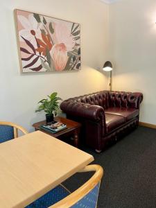 a living room with a leather couch and a table at Bright Avenue Motor Inn in Bright