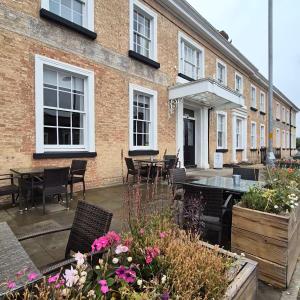 een patio met tafels, stoelen en bloemen voor een gebouw bij The Great Western Hotel in Taunton