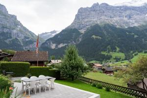 patio z białymi krzesłami i widokiem na góry w obiekcie Cosy Swiss Apartment w mieście Grindelwald