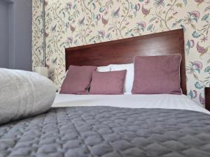 een slaapkamer met een groot bed met paarse kussens bij The Great Western Hotel in Taunton