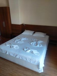 een wit bed met witte dekens en kussens erop bij Guest House Skalite in Sozopol