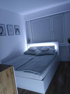 ein weißes Schlafzimmer mit einem Bett mit Licht in der Unterkunft Apartament in Ostrołęka