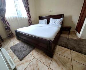 1 dormitorio con 1 cama con sábanas blancas y ventana en DF HOTEL plazza, en Yaoundé