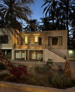 a large house with palm trees in front of it at Maison d'hôtes Dar Ranim Tozeur in Tozeur