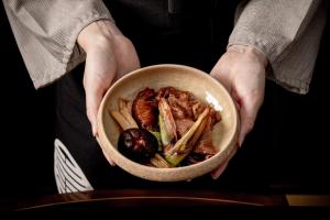 a person holding a bowl of meat and vegetables at Sui Suwako in Suwa