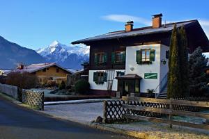 une maison avec une clôture en face d'une montagne dans l'établissement Pension Alpentraum, à Zell am See