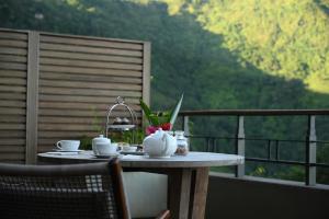 a table on a balcony with coffee cups and a view at Taj Chia Kutir Resort & Spa Darjeeling in Darjeeling