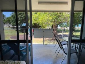 Zimmer mit Blick auf eine Terrasse mit Stühlen in der Unterkunft Whitehaven Beachfront Holiday Units in Airlie Beach