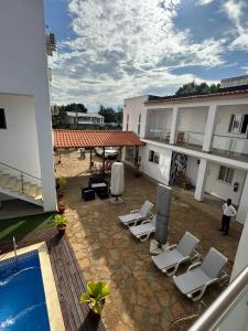 un patio extérieur avec des chaises longues et une piscine dans l'établissement Hotel Kenito, à São Tomé