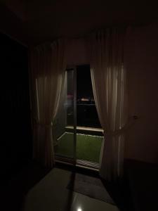 ein dunkles Zimmer mit einem Fenster mit weißen Vorhängen in der Unterkunft Eiffel Tower Apartment in Rawalpindi