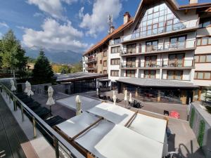 einen Balkon eines Hotels mit Tischen und Stühlen in der Unterkunft Pirin Deluxe Spa Studios in Bansko