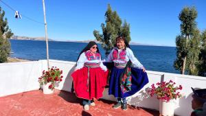 dos mujeres sentadas en una pared junto al agua en Casa munay lodge - Fernanda, en Puno