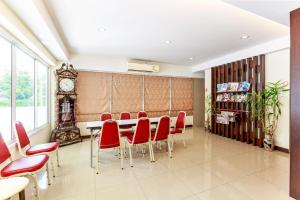 une salle à manger avec des chaises rouges, une table et une horloge dans l'établissement Capital O VResotel, à Nonthaburi