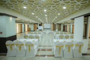 una sala de banquetes con mesas y sillas blancas en una habitación en Raj Park- Hill View, en Tirupati