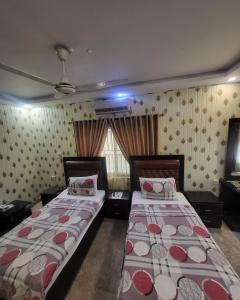 a bedroom with two beds and a window at Seaview Lodge Guest House in Karachi