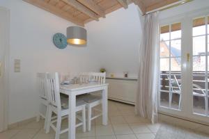 a white dining room with a table and chairs at Syltnest in Munkmarsch