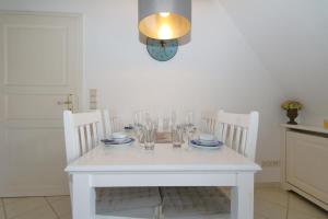 a white table with chairs and a clock on the wall at Syltnest in Munkmarsch