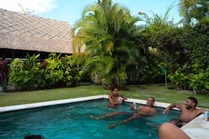 a group of men laying in a swimming pool at Bingin Bienvenue Guest House in Uluwatu