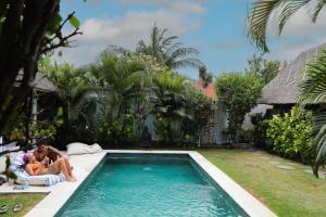 a family sitting on a raft next to a swimming pool at Bingin Bienvenue Guest House in Uluwatu