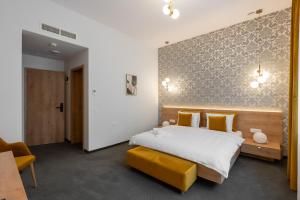 a bedroom with a king sized bed and a yellow bench at No Pardon Hotel in Satu Mare