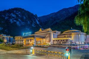 um grande edifício em frente a uma montanha à noite em Qianhe Rezen Hotel em Jiuzhaigou